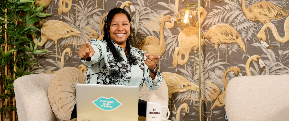 IT-professional van QISS IT zit lachend achter de laptop en wijst in de camera