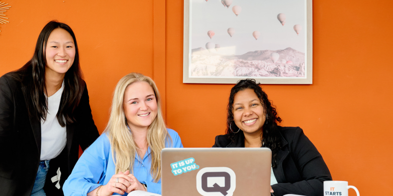 vrouwelijke IT-professionals van QISS IT zitten aan tafel met een laptop en lachen
